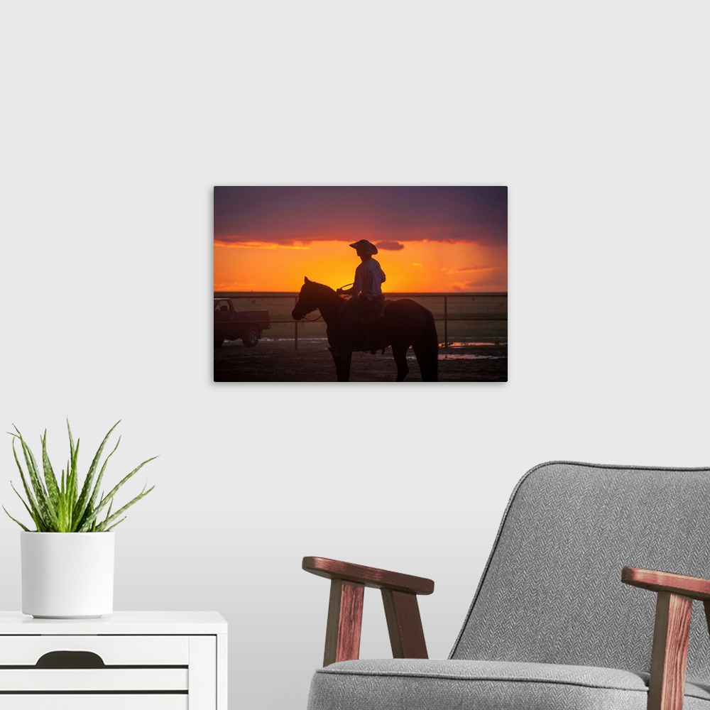 A modern room featuring Silhouette photograph of a cowboy on horseback with a beautiful purple and orange sunset in the b...