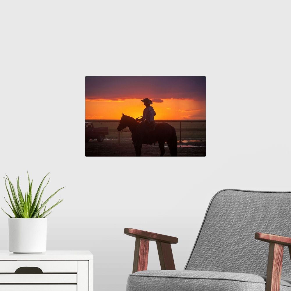 A modern room featuring Silhouette photograph of a cowboy on horseback with a beautiful purple and orange sunset in the b...
