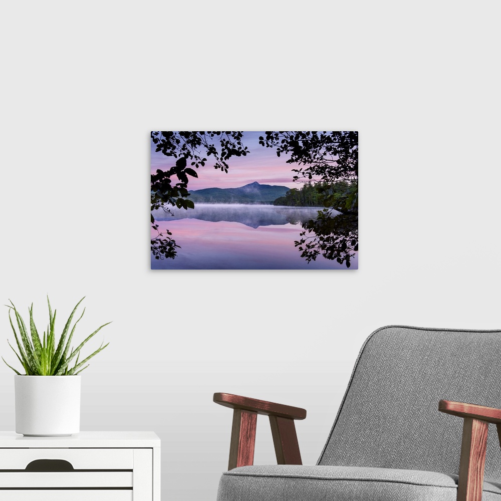 A modern room featuring Landscape photograph of a mountain view reflecting onto a foggy lake with a pink and purple sunse...