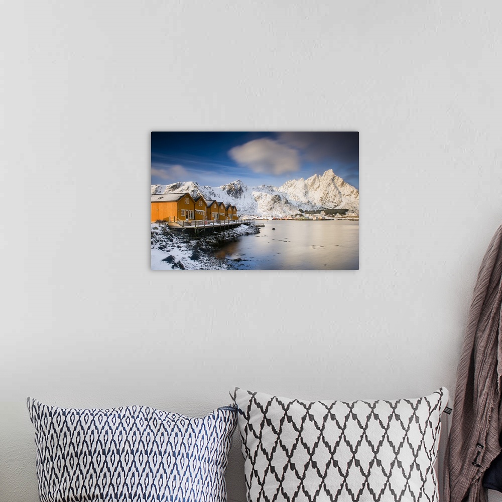 A bohemian room featuring A photograph of a Norwegian yellow cabin village seen with a mountain covered in snow in the back...