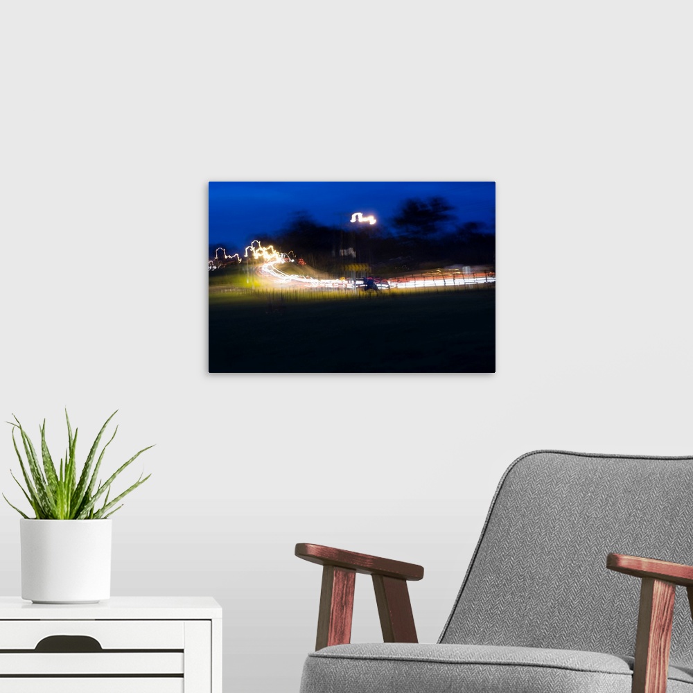 A modern room featuring Impressionist photograph of a busy country road at night with cars light painting the road.