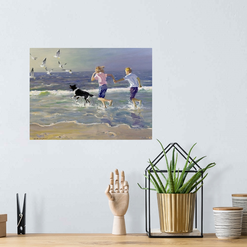 A bohemian room featuring Painting of two children holding hands running on the beach as a dog chases birds in front of the...