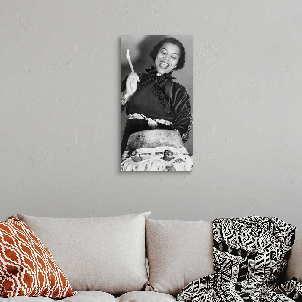 A bohemian room featuring Zora Hurston beating the hountar, or mama drum. 1937 (photo) by American Photographer, (20th cent...