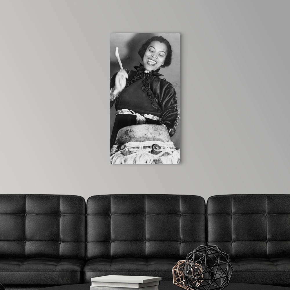 A modern room featuring Zora Hurston beating the hountar, or mama drum. 1937 (photo) by American Photographer, (20th cent...