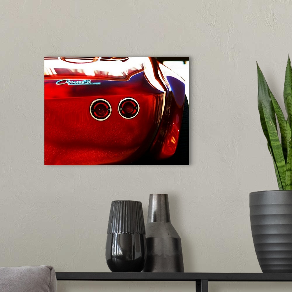 A modern room featuring Photograph of the rear and break lights of a red 1963 Corvette Stingray 15.