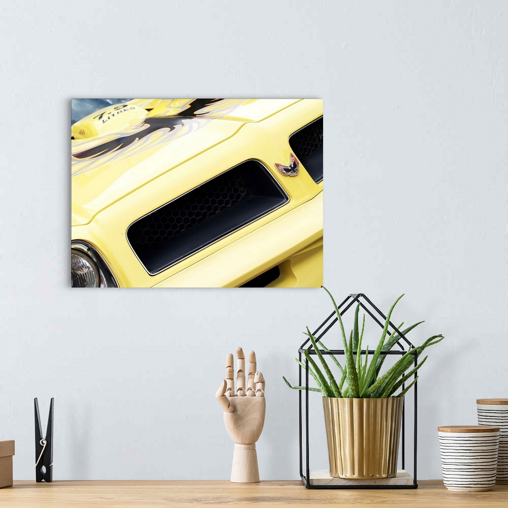 A bohemian room featuring Angled photograph of the front of a yellow 1976 Pontiac Trans Am.