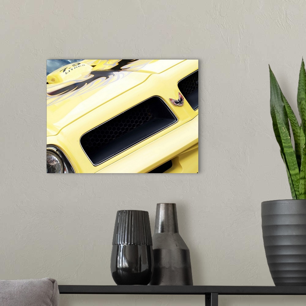 A modern room featuring Angled photograph of the front of a yellow 1976 Pontiac Trans Am.