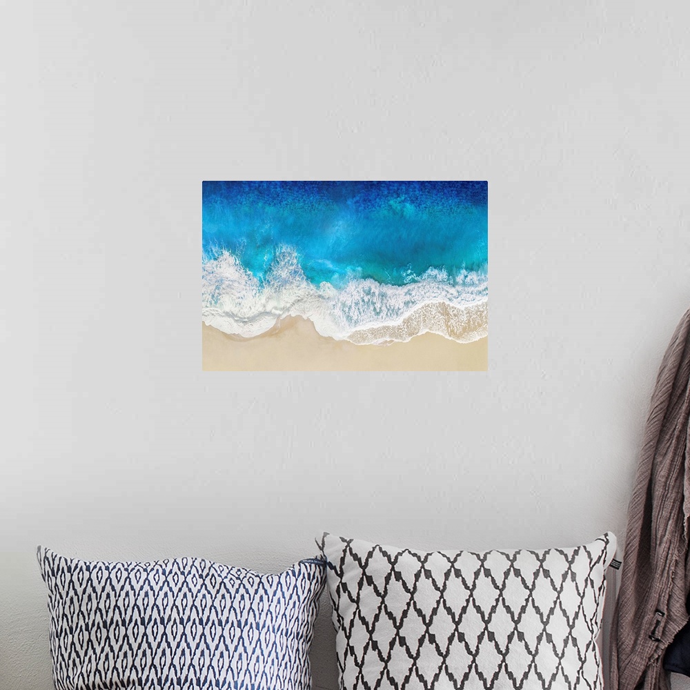 A bohemian room featuring One artwork in a series of aerial shots of a beach as blue waves break upon the shore.