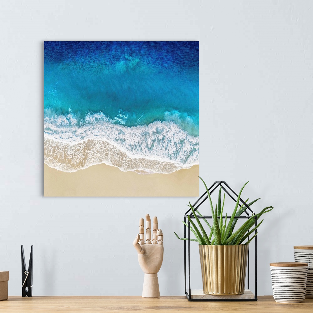 A bohemian room featuring One artwork in a series of aerial shots of a beach as blue waves break upon the shore.