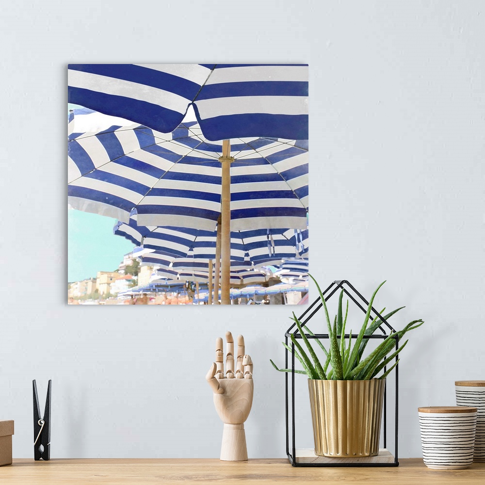 A bohemian room featuring Square decor with blue and white striped beach umbrellas lined up on the beach.