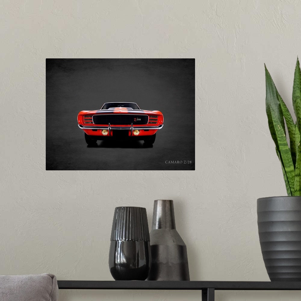 A modern room featuring Photograph of a red 1969 Chevrolet Camaro Z28 printed on a black background with a dark vignette.