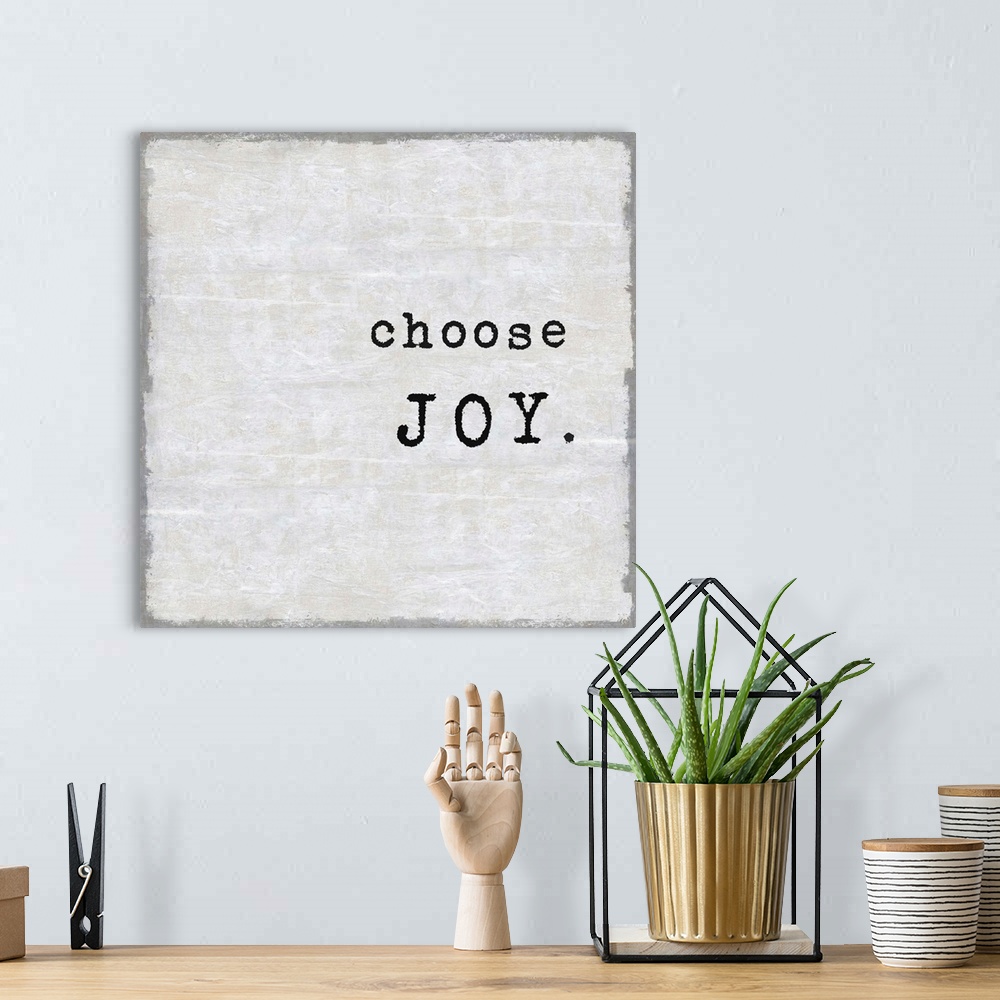A bohemian room featuring "Choose Joy" on a square background in shades of gray.