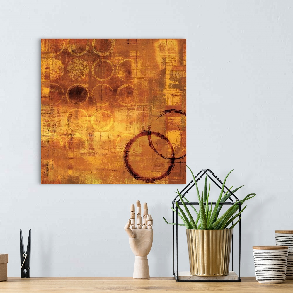 A bohemian room featuring Gold square abstract painting with gold circles and two red circles on the bottom right side.