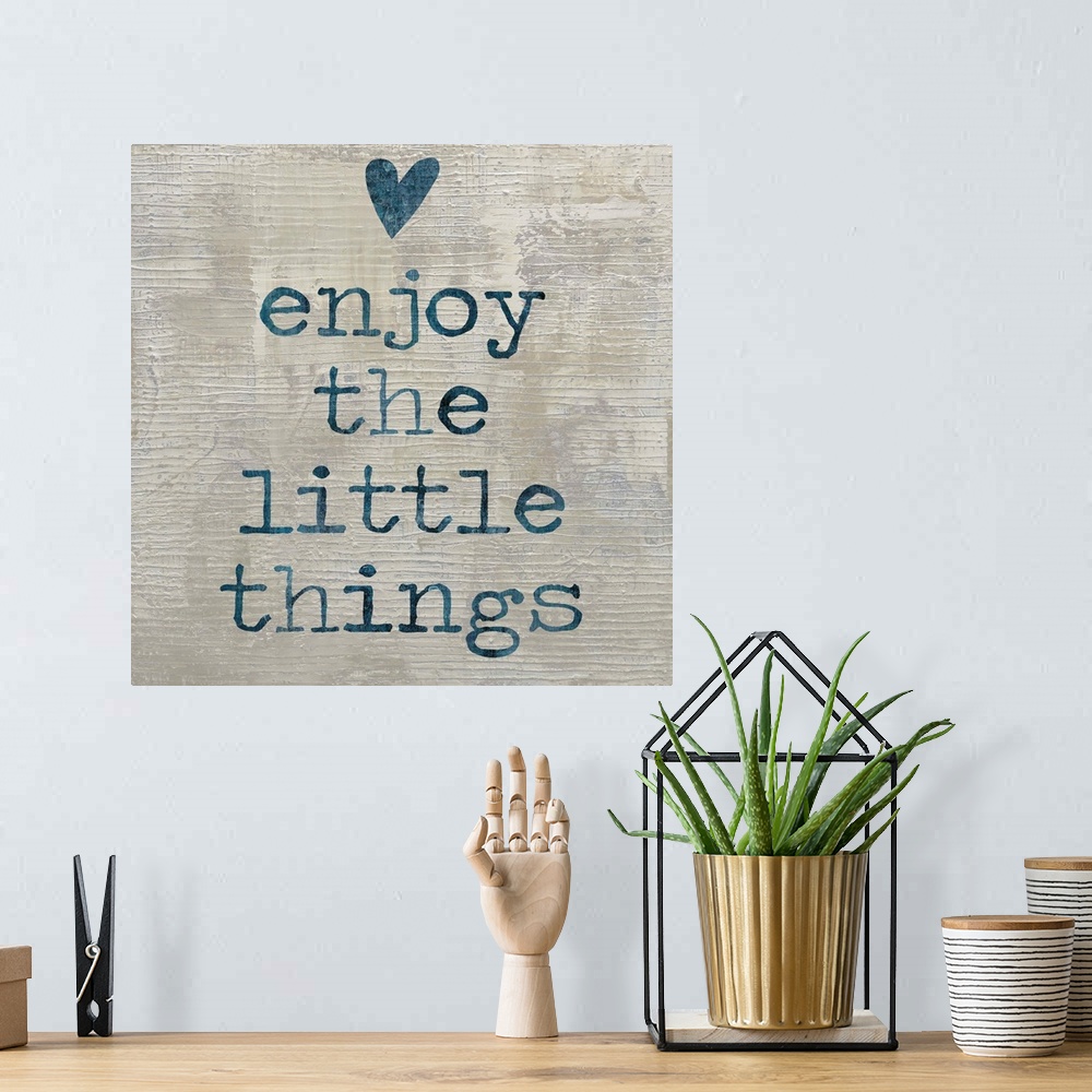 A bohemian room featuring "enjoy the little things" written in blue with a heart above, on a textured neutral colored backg...