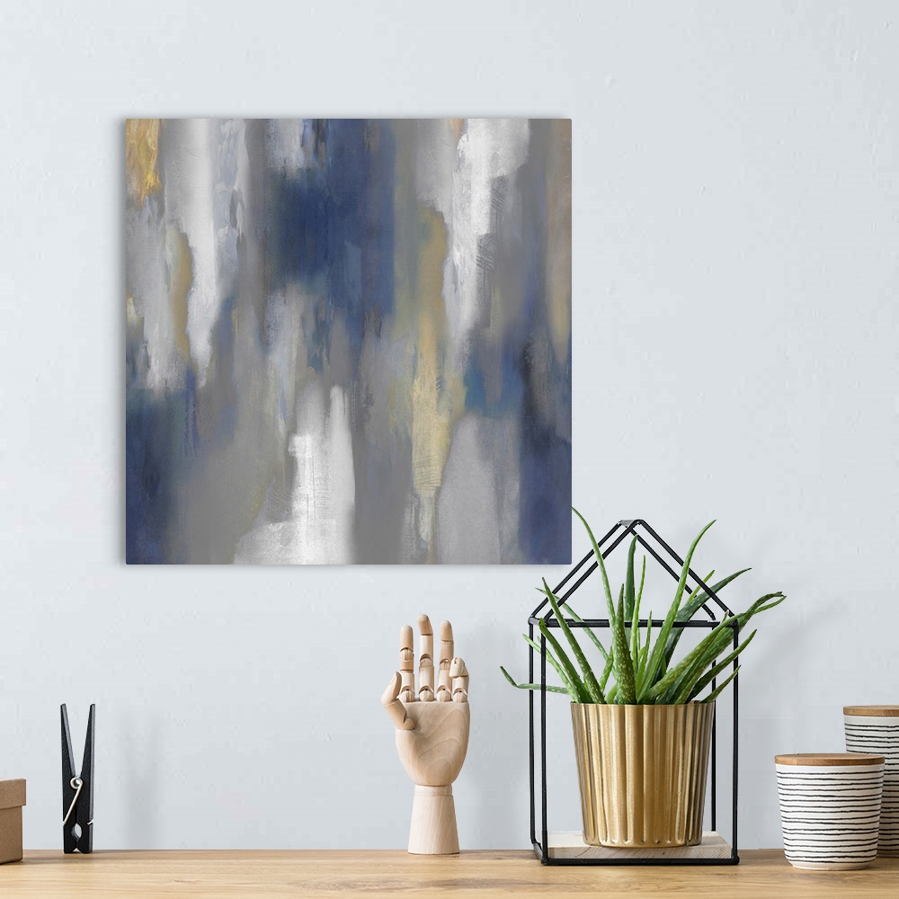 A bohemian room featuring Square abstract painting with hazy shades of blue, gray, white, and gold smearing down the canvas.