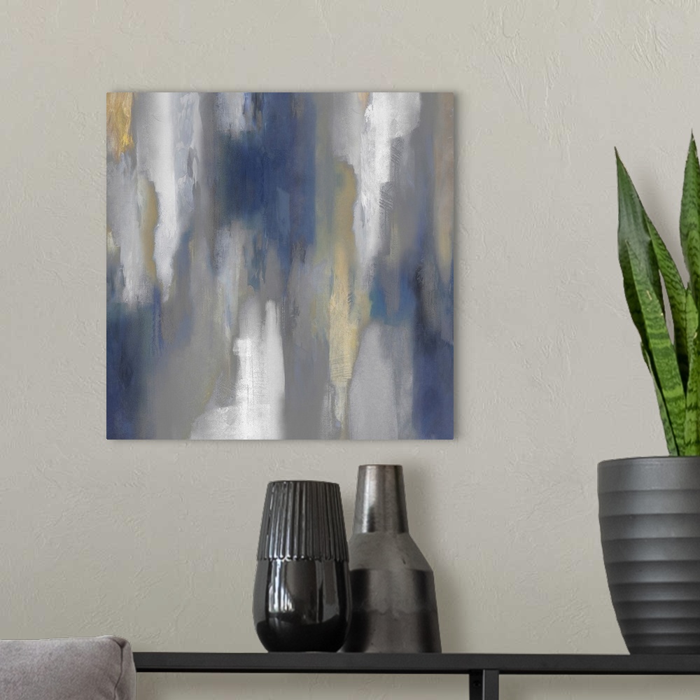 A modern room featuring Square abstract painting with hazy shades of blue, gray, white, and gold smearing down the canvas.