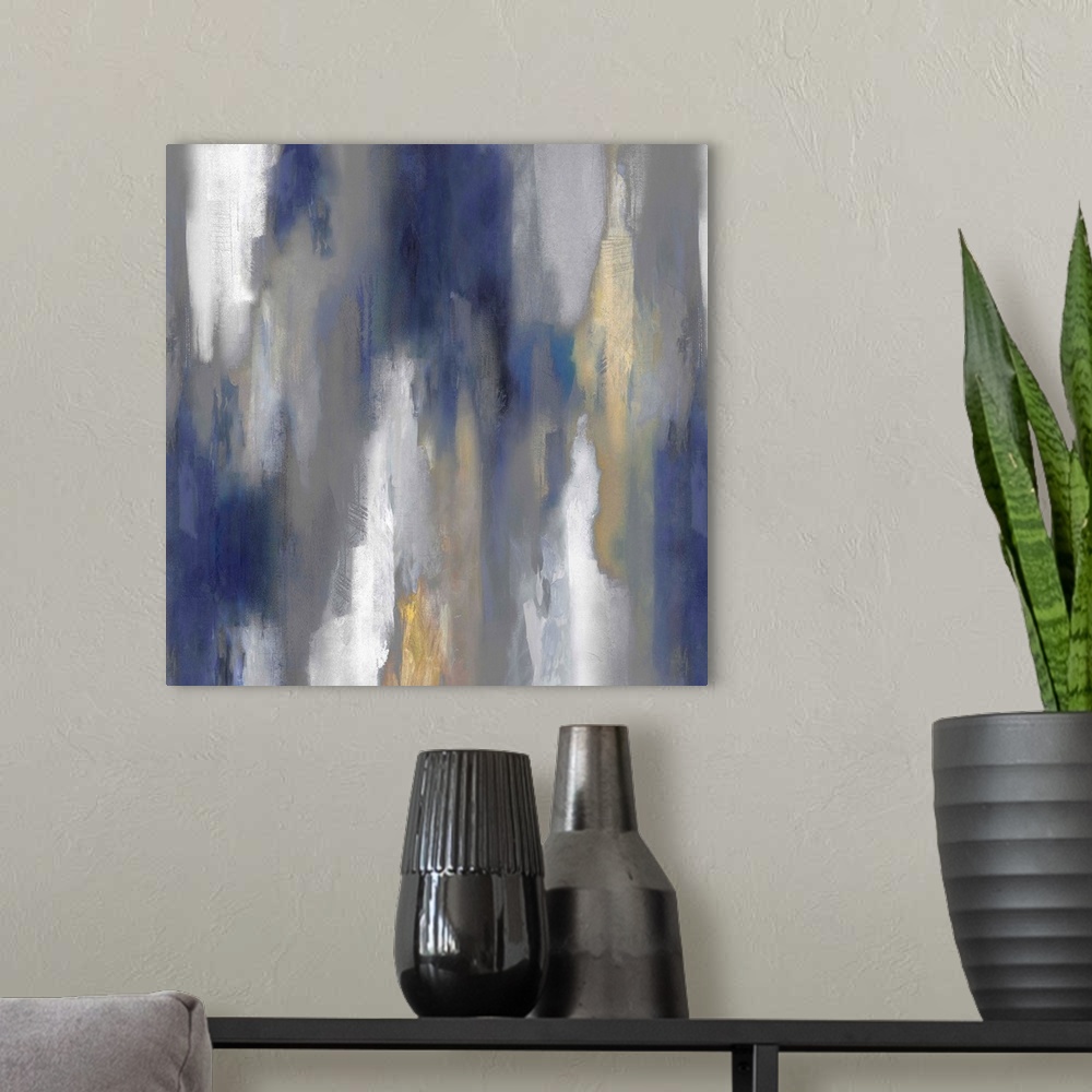 A modern room featuring Square abstract painting with hazy shades of blue, gray, white, and gold smearing down the canvas.