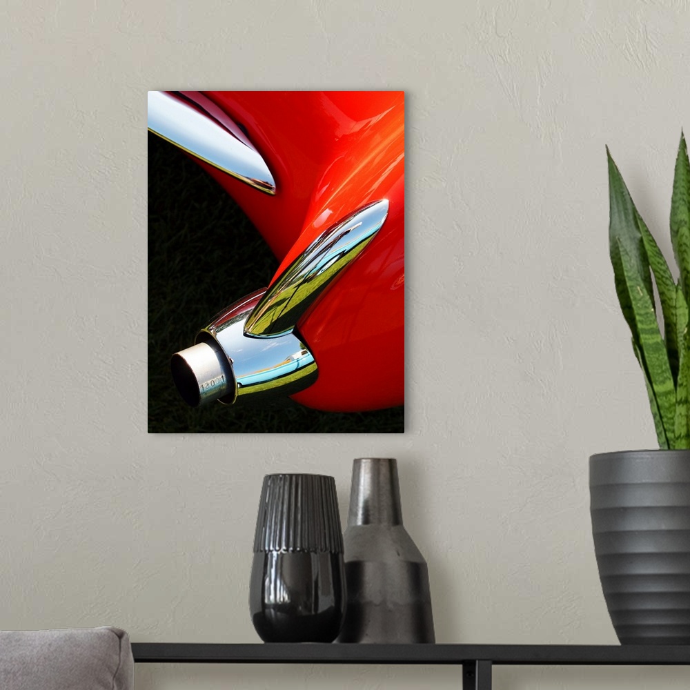 A modern room featuring Photograph of the rear exhaust on a red 1956 Corvette.