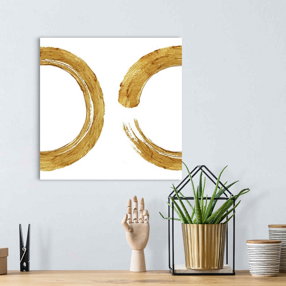 A bohemian room featuring This Zen artwork features two sweeping circular brush strokes in gold over a white background.