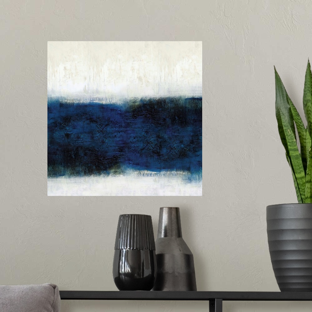 A modern room featuring Square abstract painting with a band of deep blue hues in the middle and off-white with tan above...