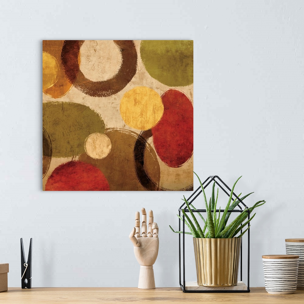 A bohemian room featuring Square abstract art created with red, green, gold, and brown circular shapes on a neutral colored...