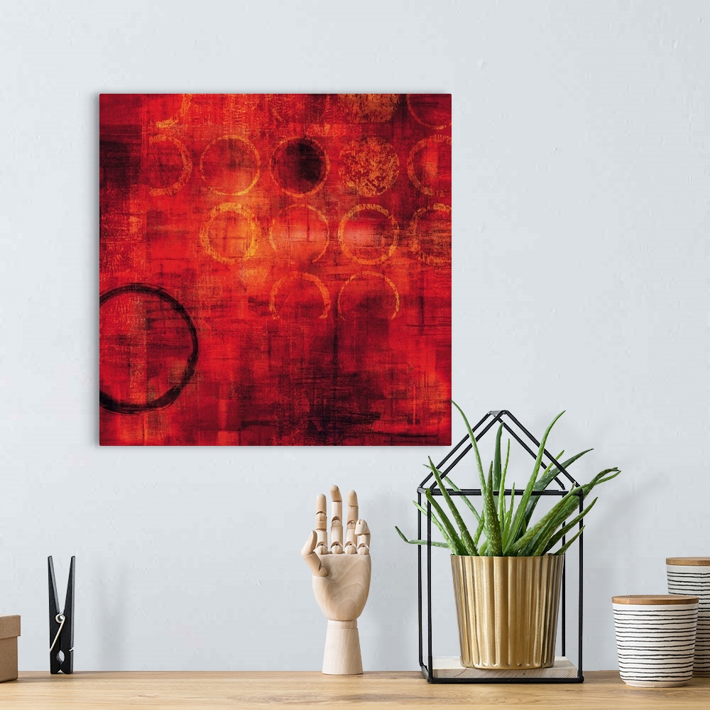 A bohemian room featuring Bright red square abstract painting with gold circles and one black circle on the bottom left side.