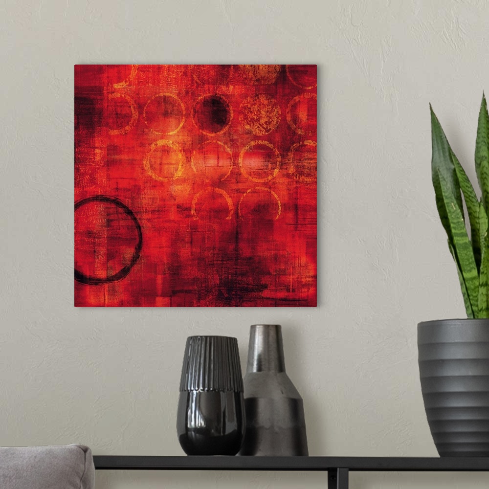 A modern room featuring Bright red square abstract painting with gold circles and one black circle on the bottom left side.