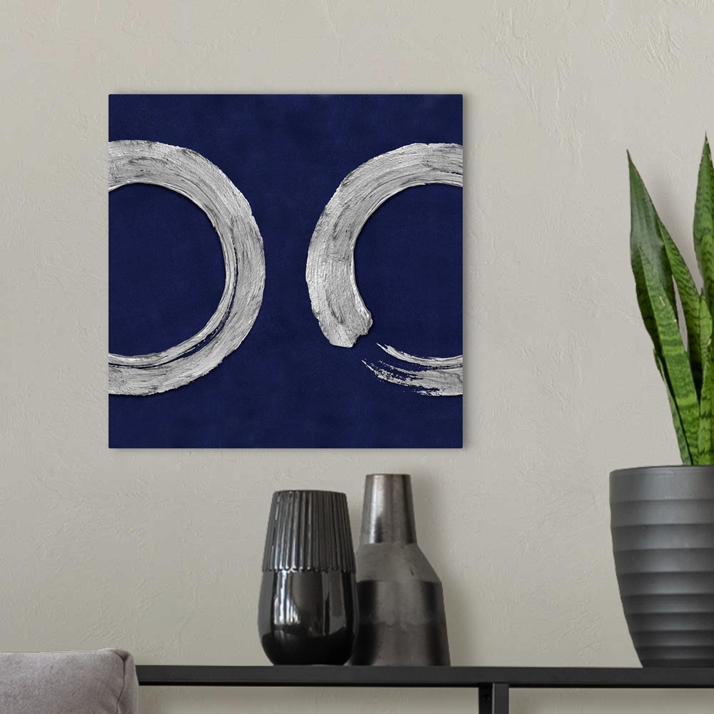 A modern room featuring This Zen artwork features two sweeping circular brush strokes in silver over a mottled blue backg...