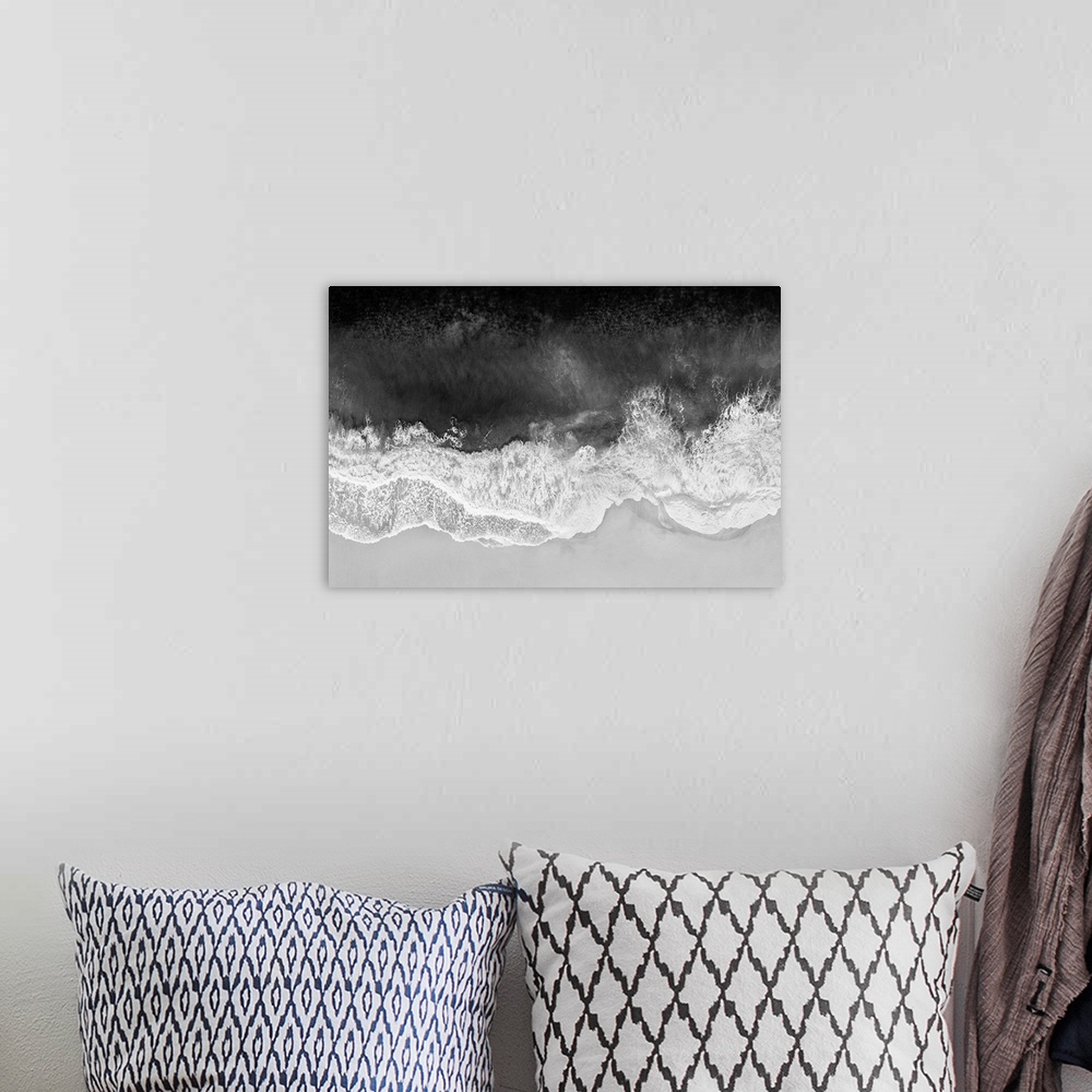 A bohemian room featuring One artwork in a series of aerial shots of a beach as dark gray waves break upon the shore.