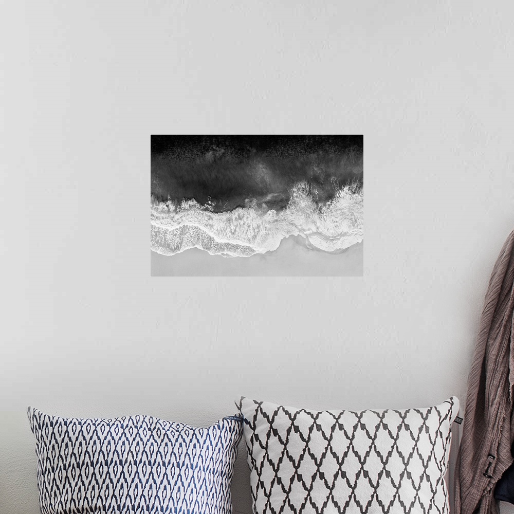 A bohemian room featuring One artwork in a series of aerial shots of a beach as dark gray waves break upon the shore.