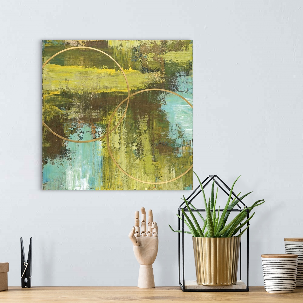A bohemian room featuring Square abstract of two circular rings in gold with a textured background of green and blue.