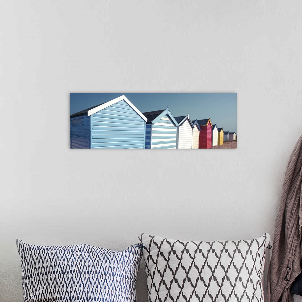A bohemian room featuring A panoramic image of a long line of colorful beach huts on a clear day.