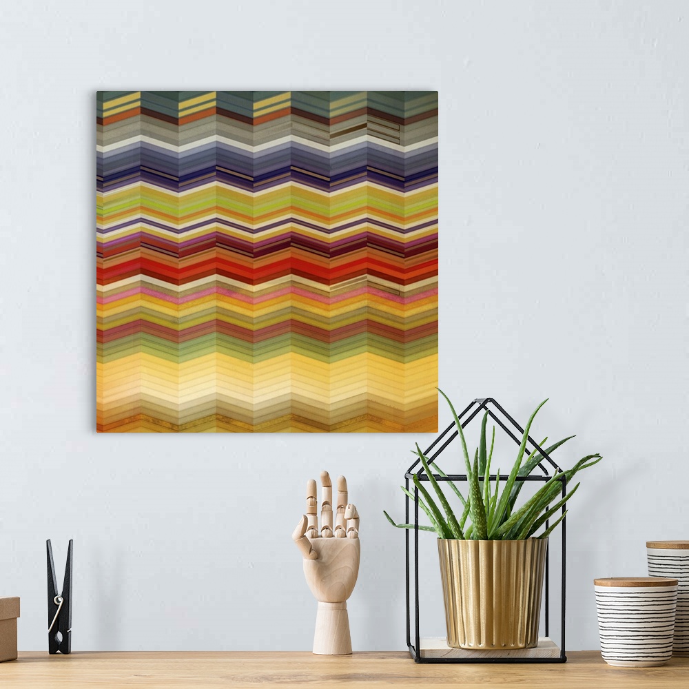 A bohemian room featuring Square artwork of a repetitive chevron pattern in multi-colors of muted colors.