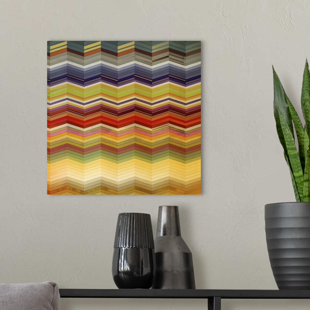 A modern room featuring Square artwork of a repetitive chevron pattern in multi-colors of muted colors.