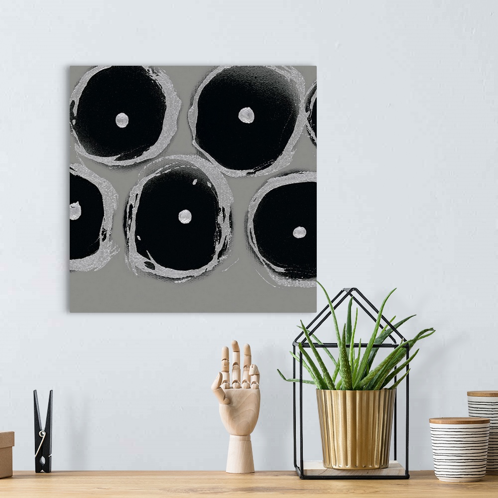 A bohemian room featuring A square abstract of circular shapes with dots in the center in shades of light gray and black.