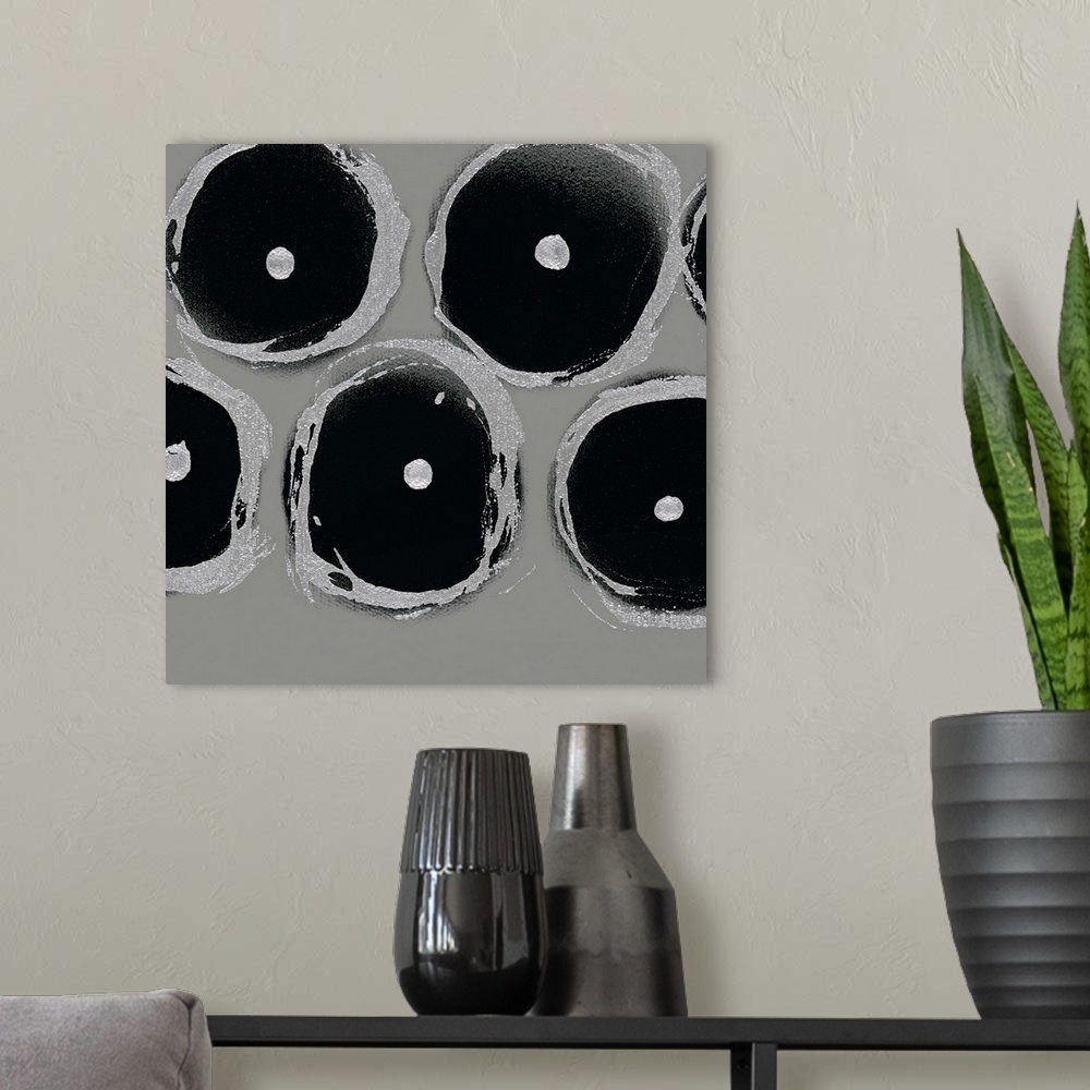A modern room featuring A square abstract of circular shapes with dots in the center in shades of light gray and black.