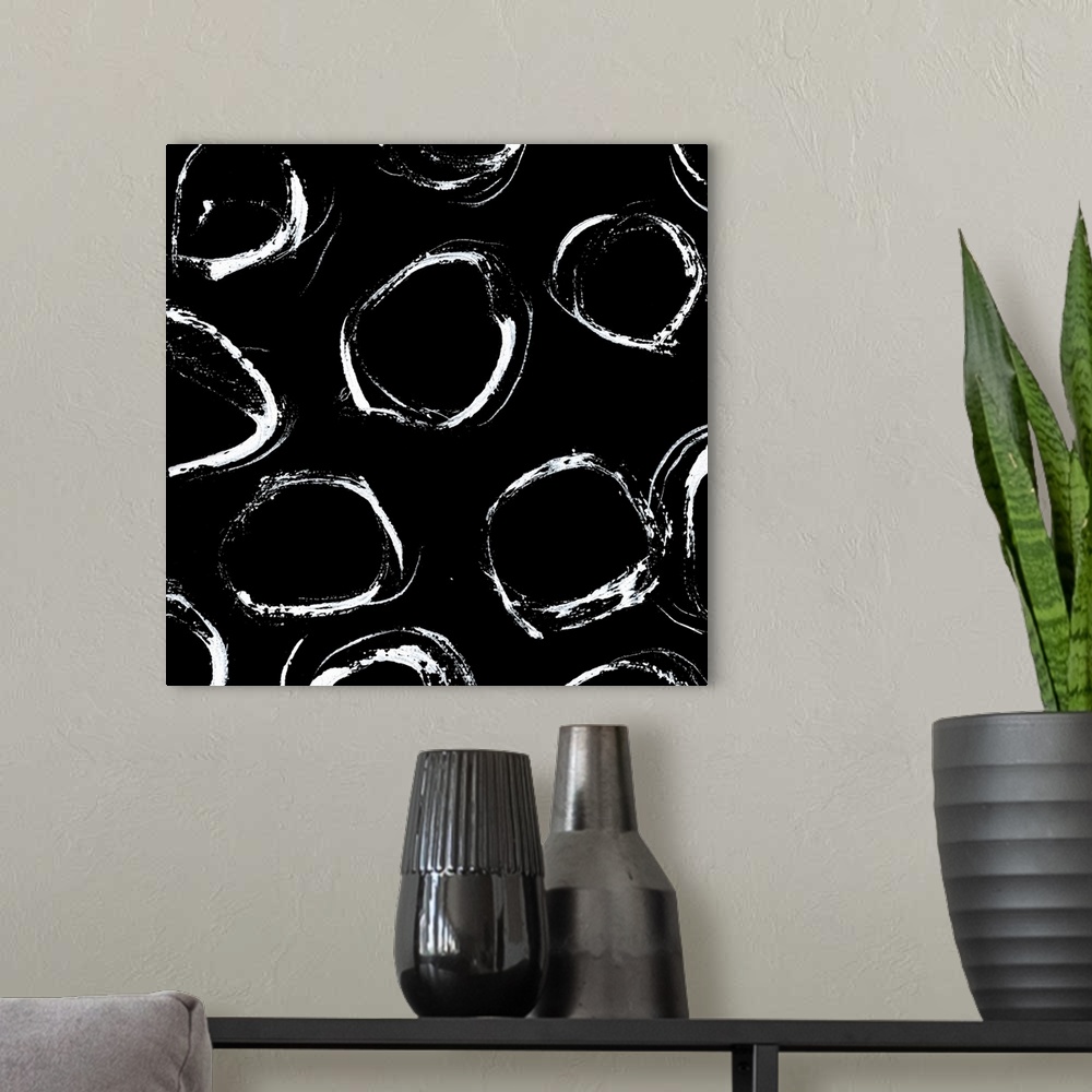 A modern room featuring A square abstract of unrefined white circles against a black backdrop.