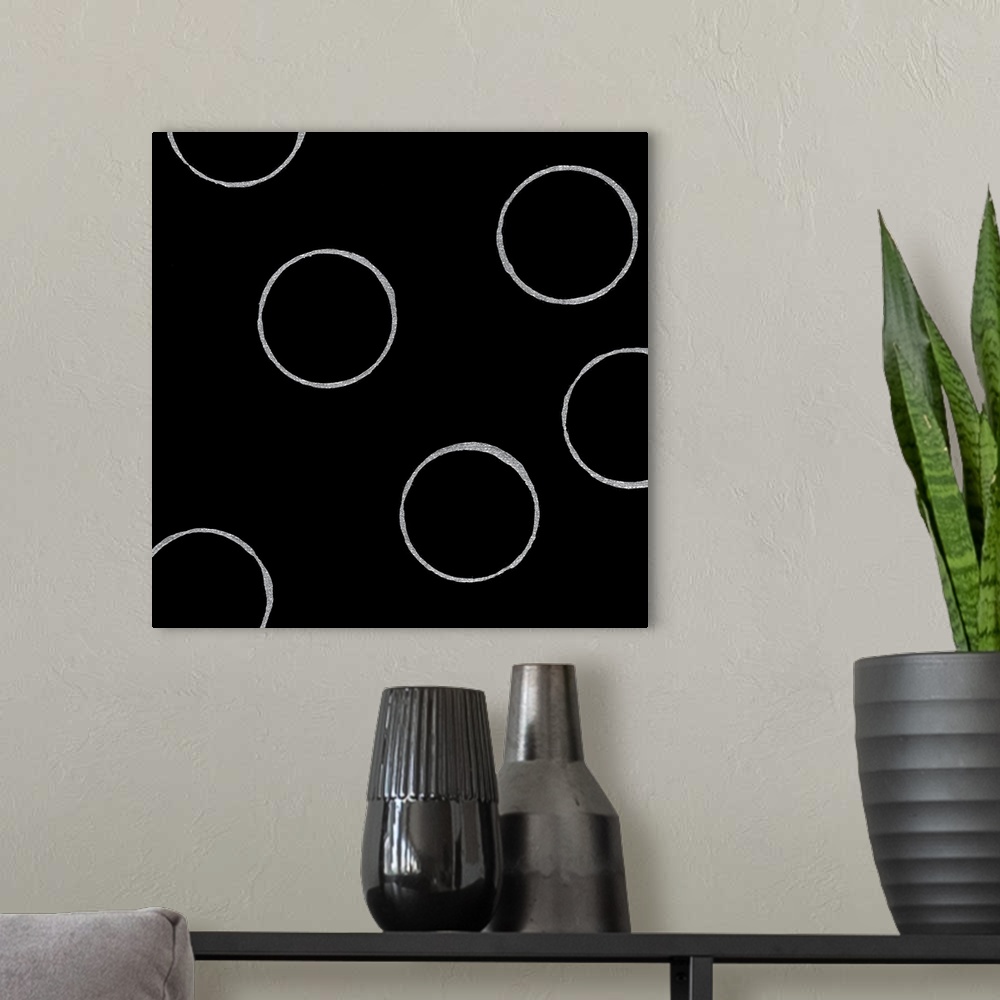 A modern room featuring A square abstract of textured white circles against a black backdrop.