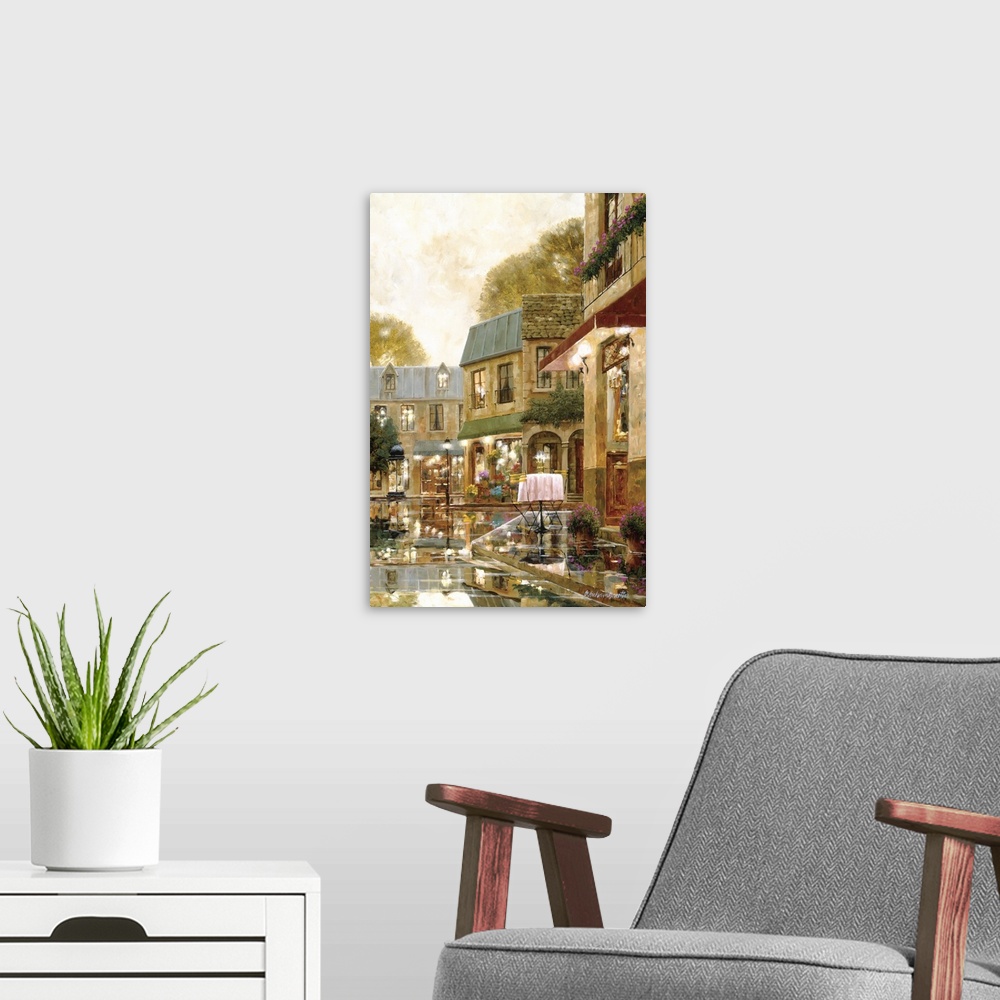 A modern room featuring Vertical artwork of a evening street scene in Europe of a single table outside of a restaurant wi...