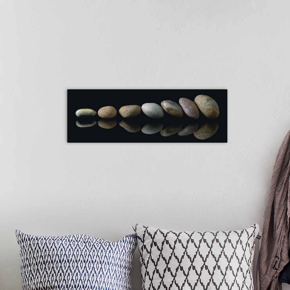 A bohemian room featuring A panoramic photograph of a row of smooth rocks leaning against each other.