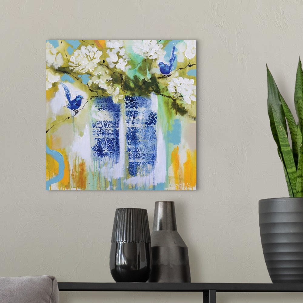 A modern room featuring Square painting of two vases, with a blue floral design, full of white flowers and two blue birds...