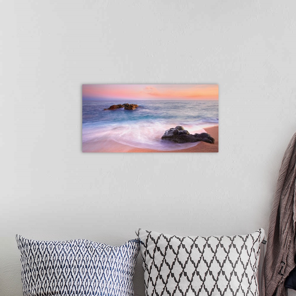 A bohemian room featuring Panoramic image of gentle waves on a rocky seashore with a vibrant pink sunset.