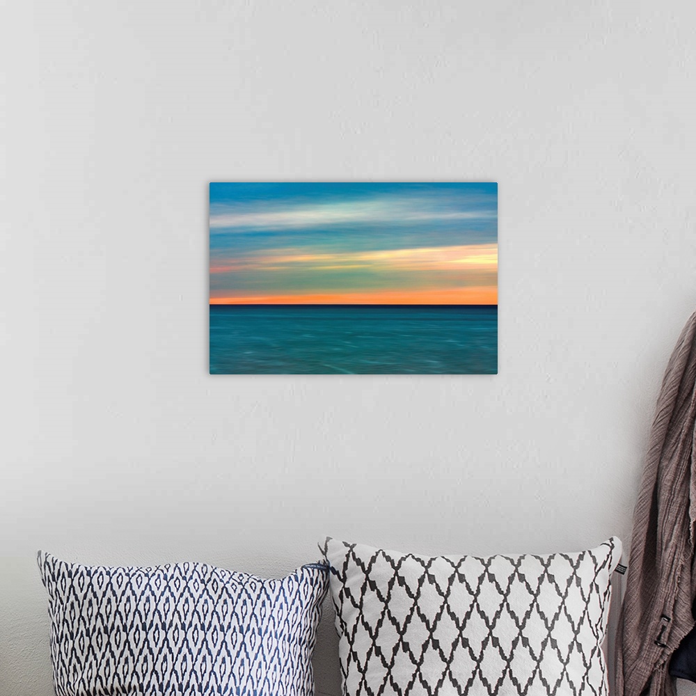 A bohemian room featuring Horizontal image of a color sunset over calm ocean waters.