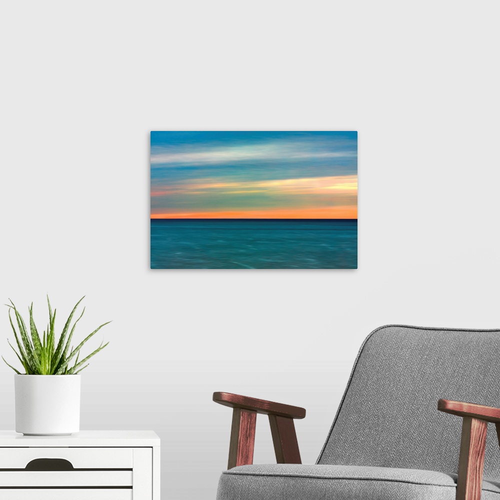 A modern room featuring Horizontal image of a color sunset over calm ocean waters.