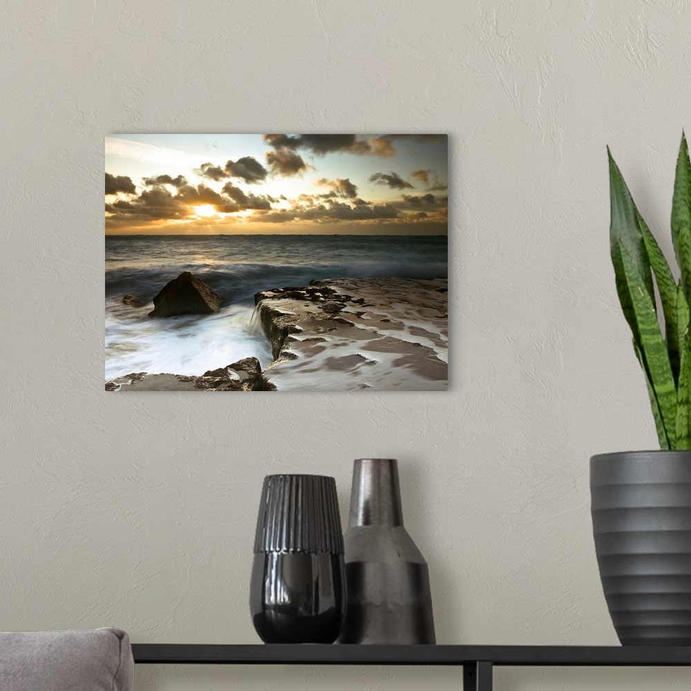 A modern room featuring Image of a rocky coastline during a cloudy sunset.