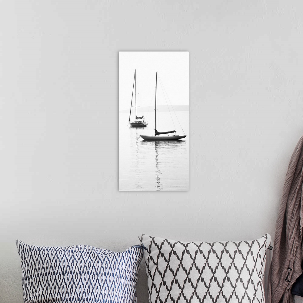 A bohemian room featuring Black and white photograph of two sailboats with sails down on calm water.