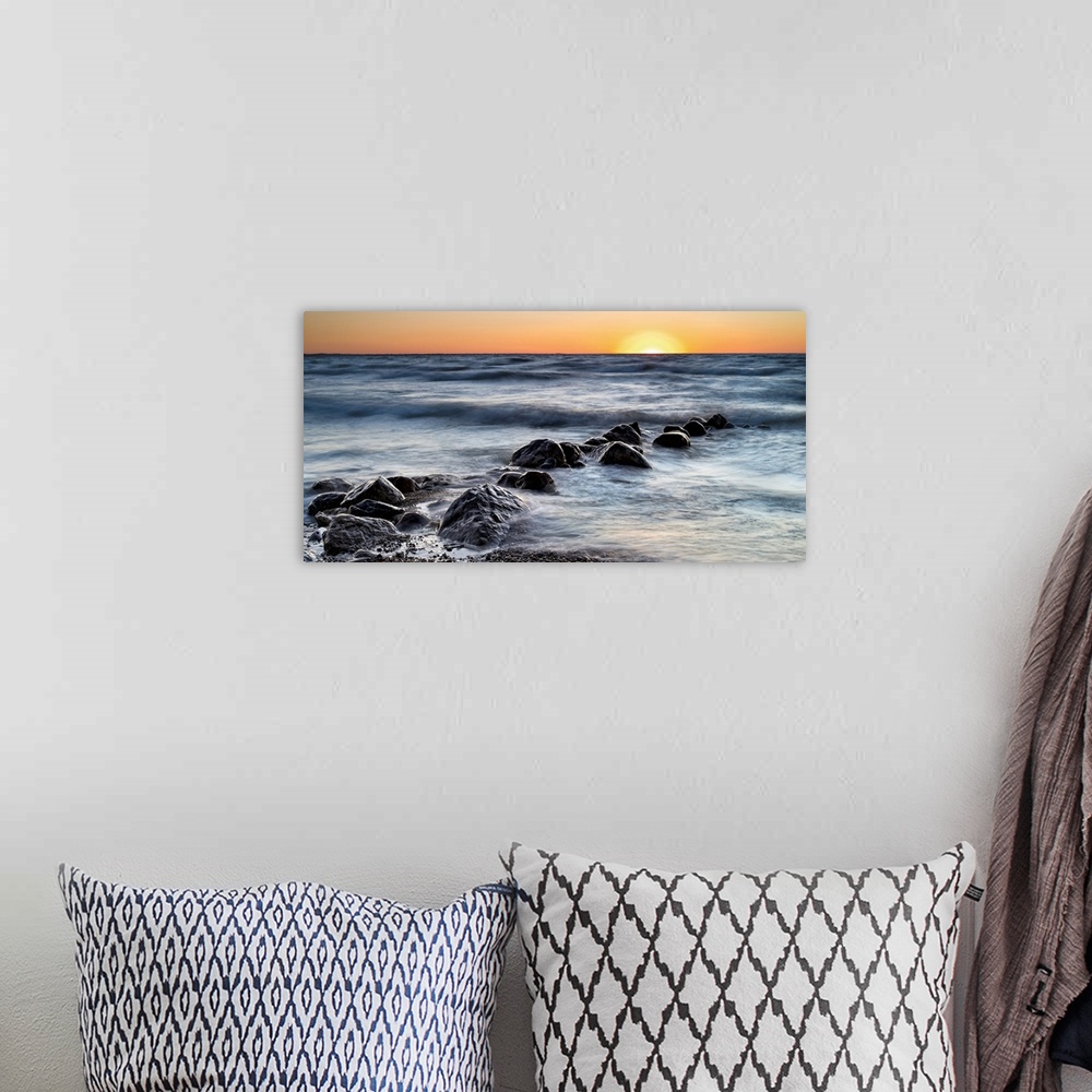A bohemian room featuring Photograph of a line of rocks in the surf of a beach during sunset.