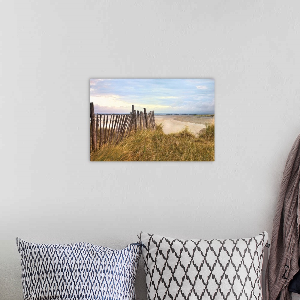 A bohemian room featuring Photograph of beach with grass covered dunes, on a cloudy day.