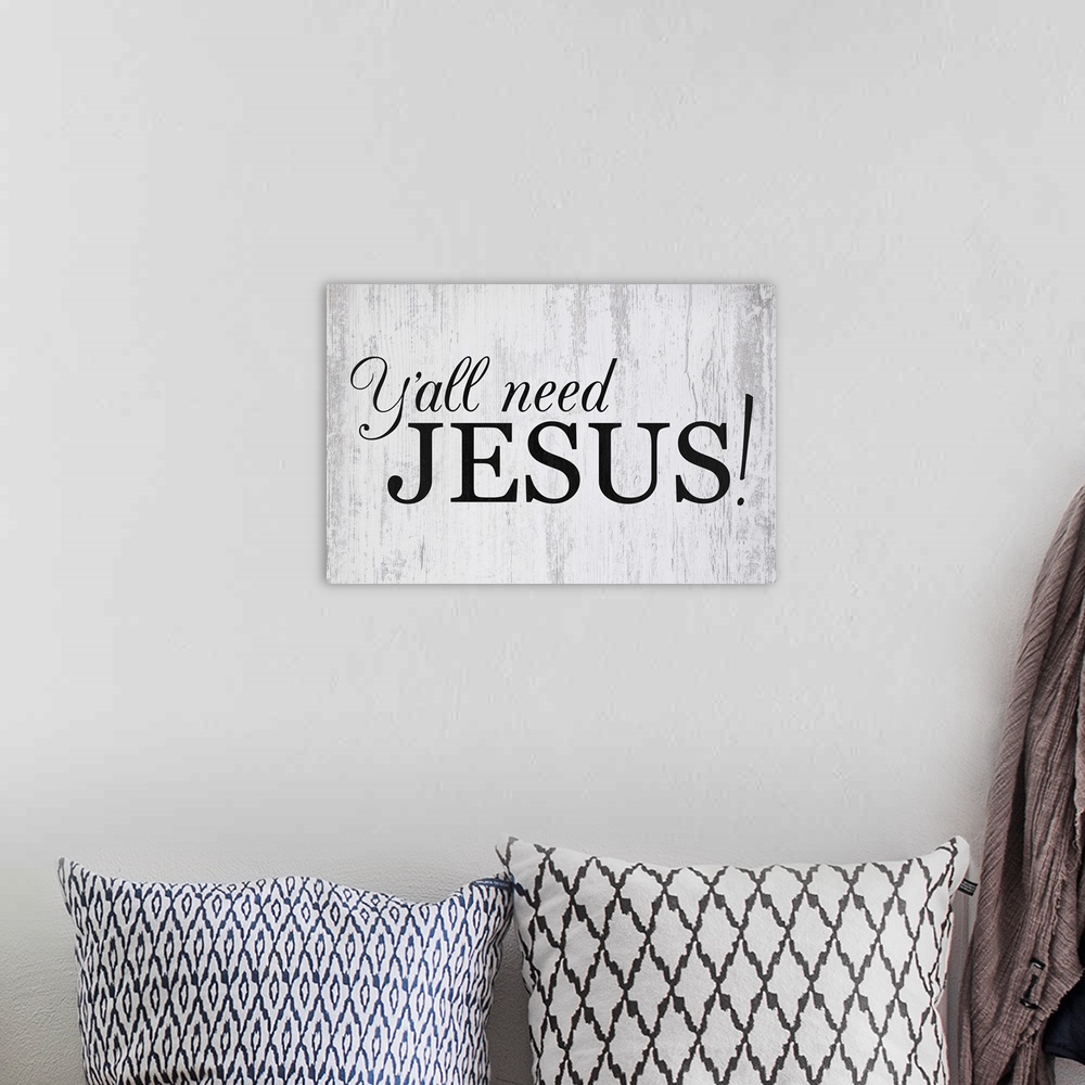 A bohemian room featuring "Ya'll Need Jesus" in black on a gray wood backdrop.