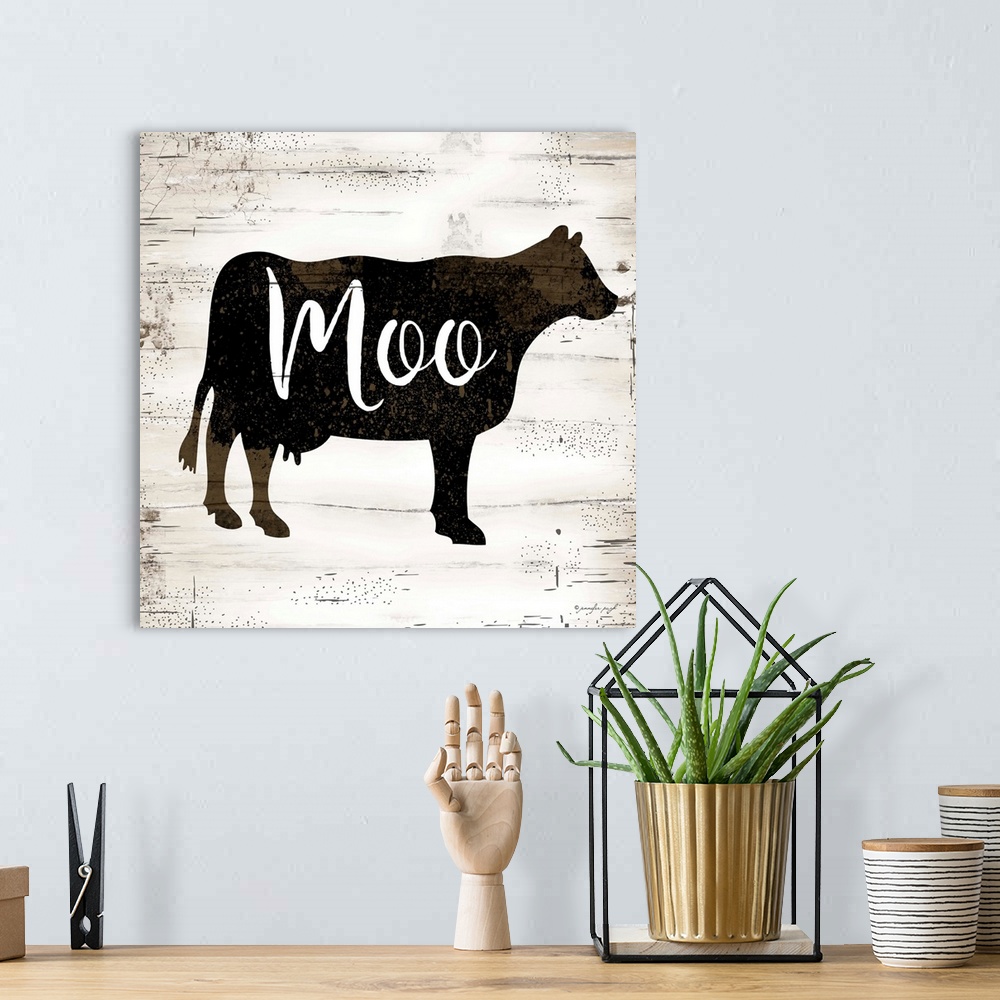 A bohemian room featuring Graphic art of the silhouette of a cow with script text overlapping it, on a a horizontally strip...